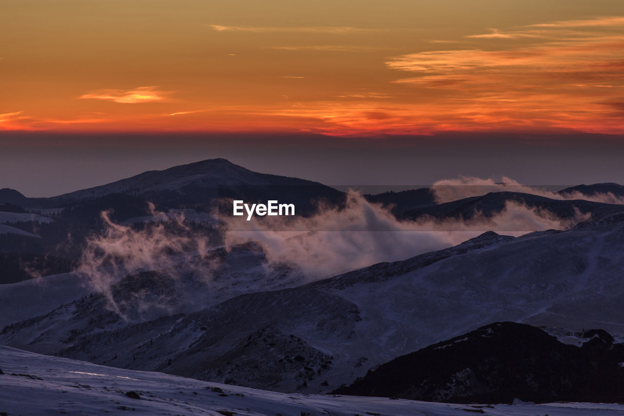 Scenic view of snowcapped mountains against sky during sunset