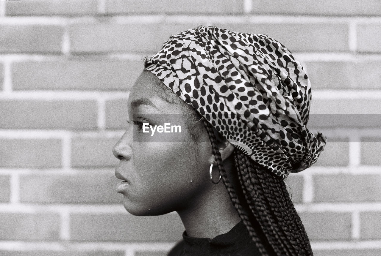 Side view of woman against brick wall