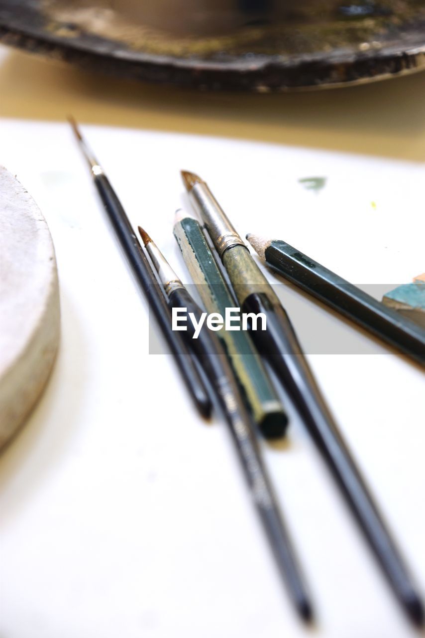 HIGH ANGLE VIEW OF PAINTBRUSHES IN CONTAINER ON TABLE