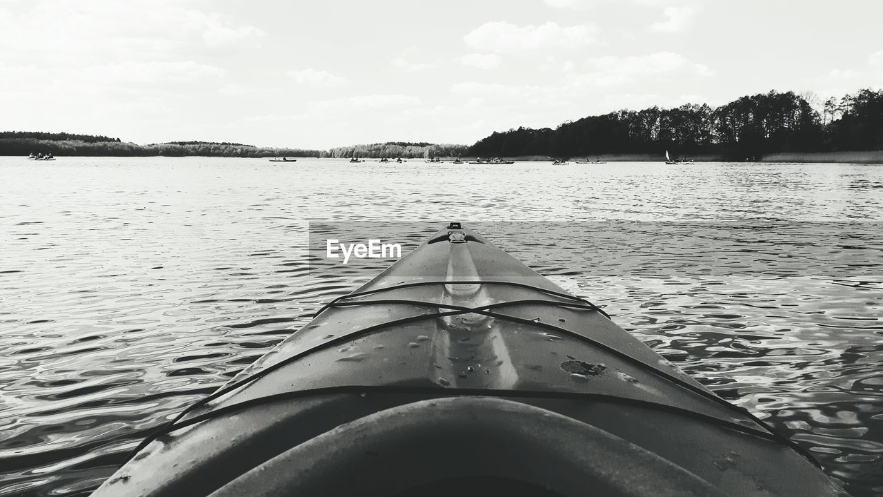 BOATS MOORED IN LAKE AGAINST SKY