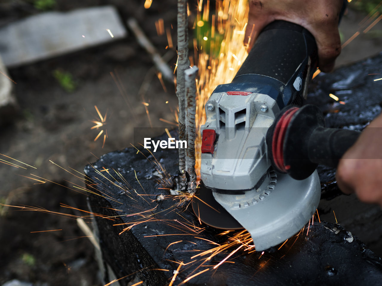 Worker cuts off excess reinforcement in the foundation using an angle grinder, metal sparks fly