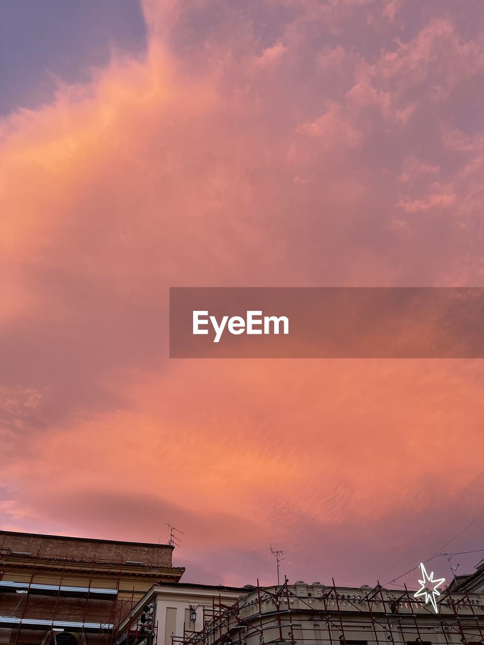 LOW ANGLE VIEW OF BUILDINGS AGAINST CLOUDY SKY DURING SUNSET