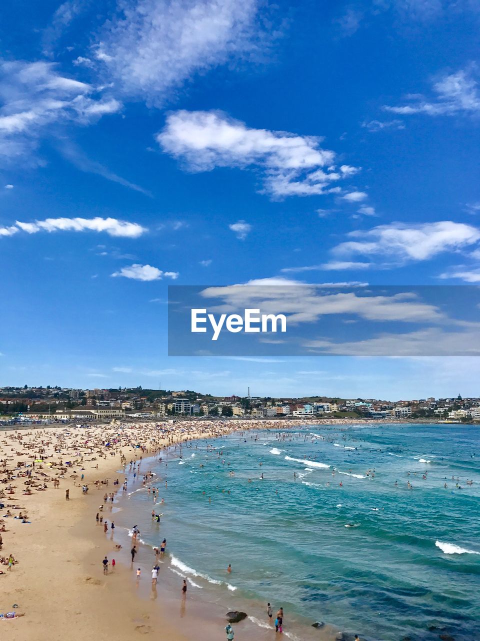 People enjoying at beach against blue sky