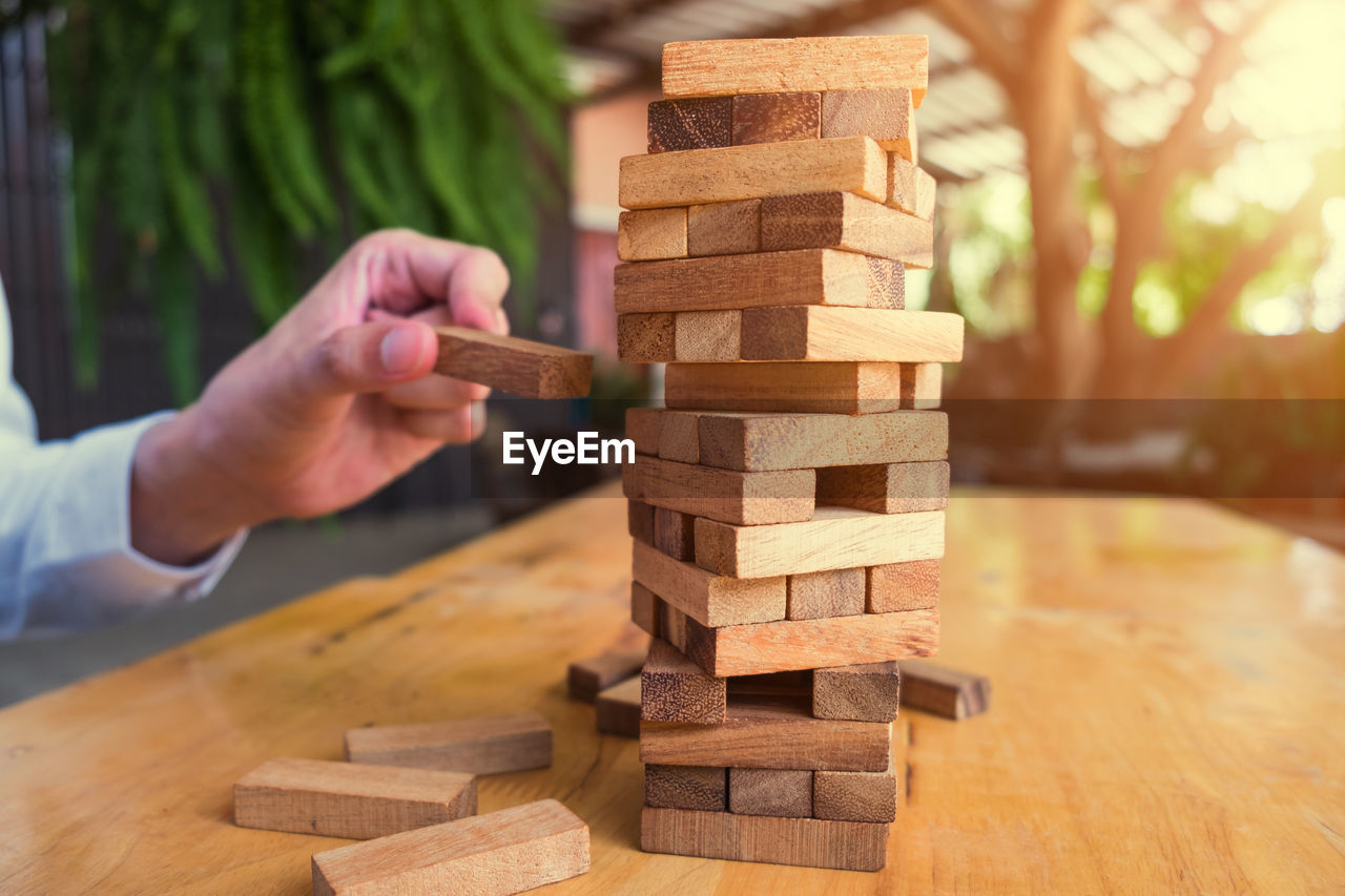 Cropped image of business person playing block removal game on table