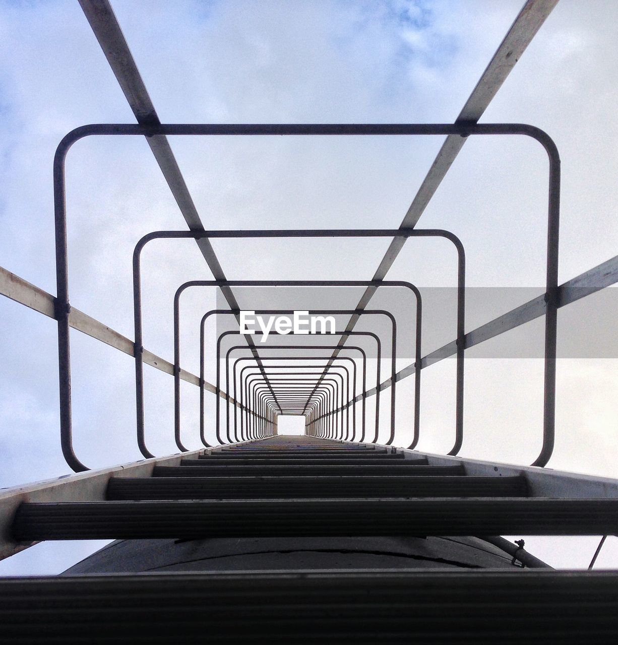 Low angle view of ladder against cloudy sky