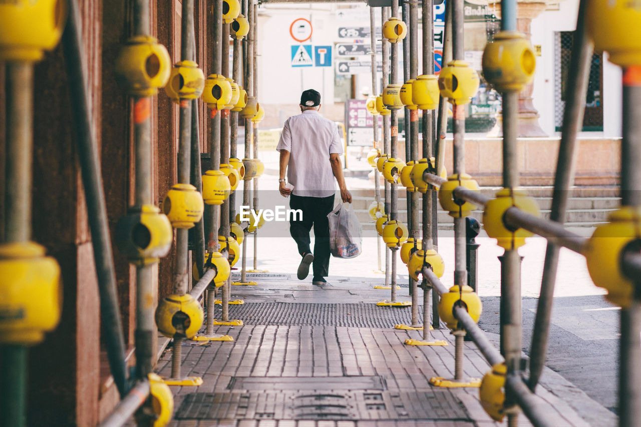 Rear view of man walking with bag on street