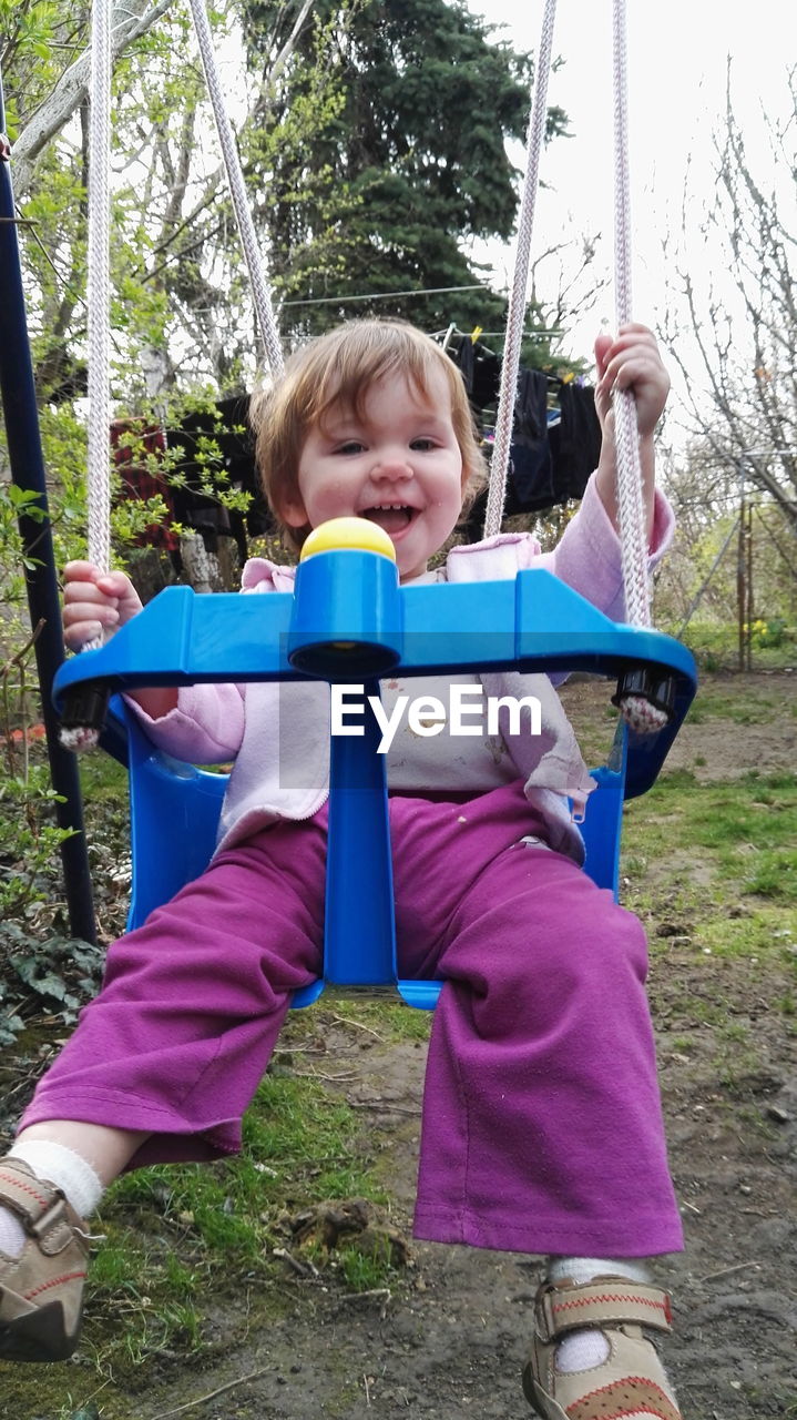 Portrait of cute baby girl on swing in back yard