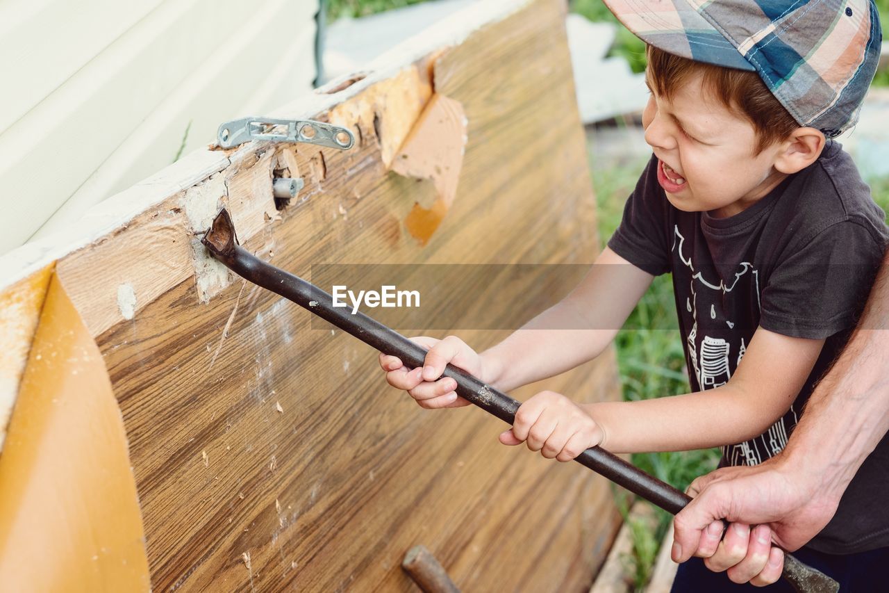 Pulling nails out of the board. strong boy face. 