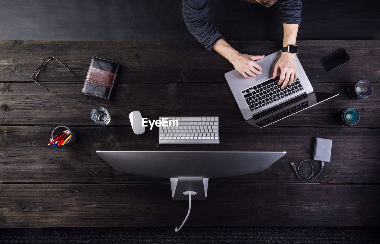 Man working at desk with computer and various digital gadgets