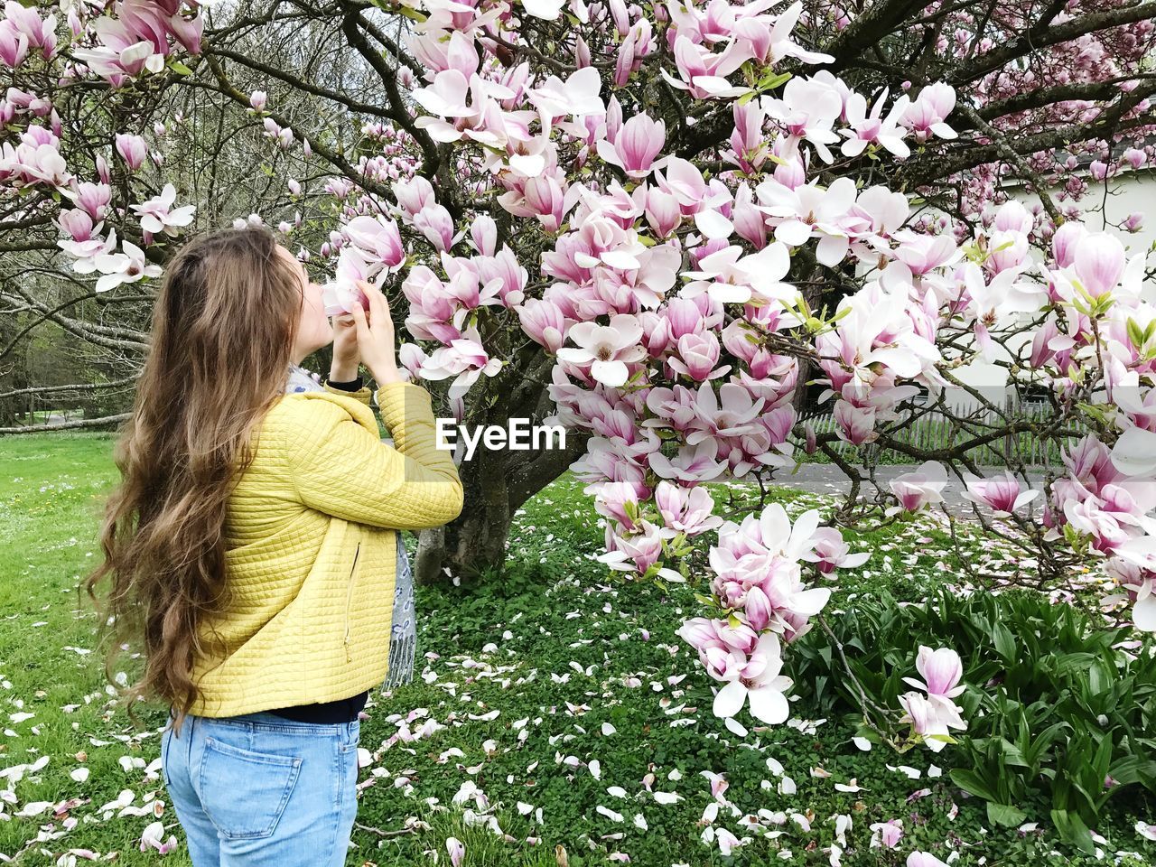 Young woman smelling flowers on tree