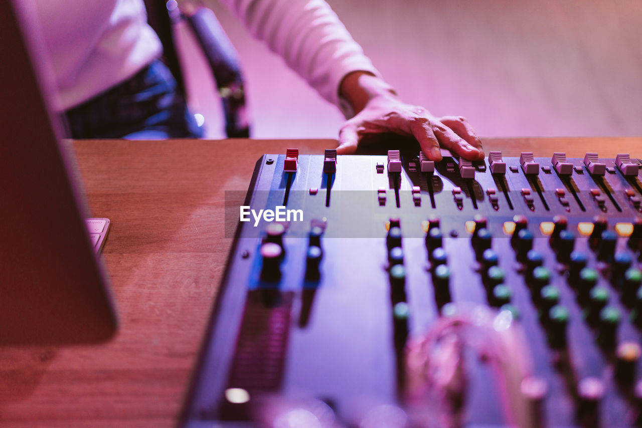 Close up producer woman hands nearby soundboard is mixing, adjusting and editing sounds.