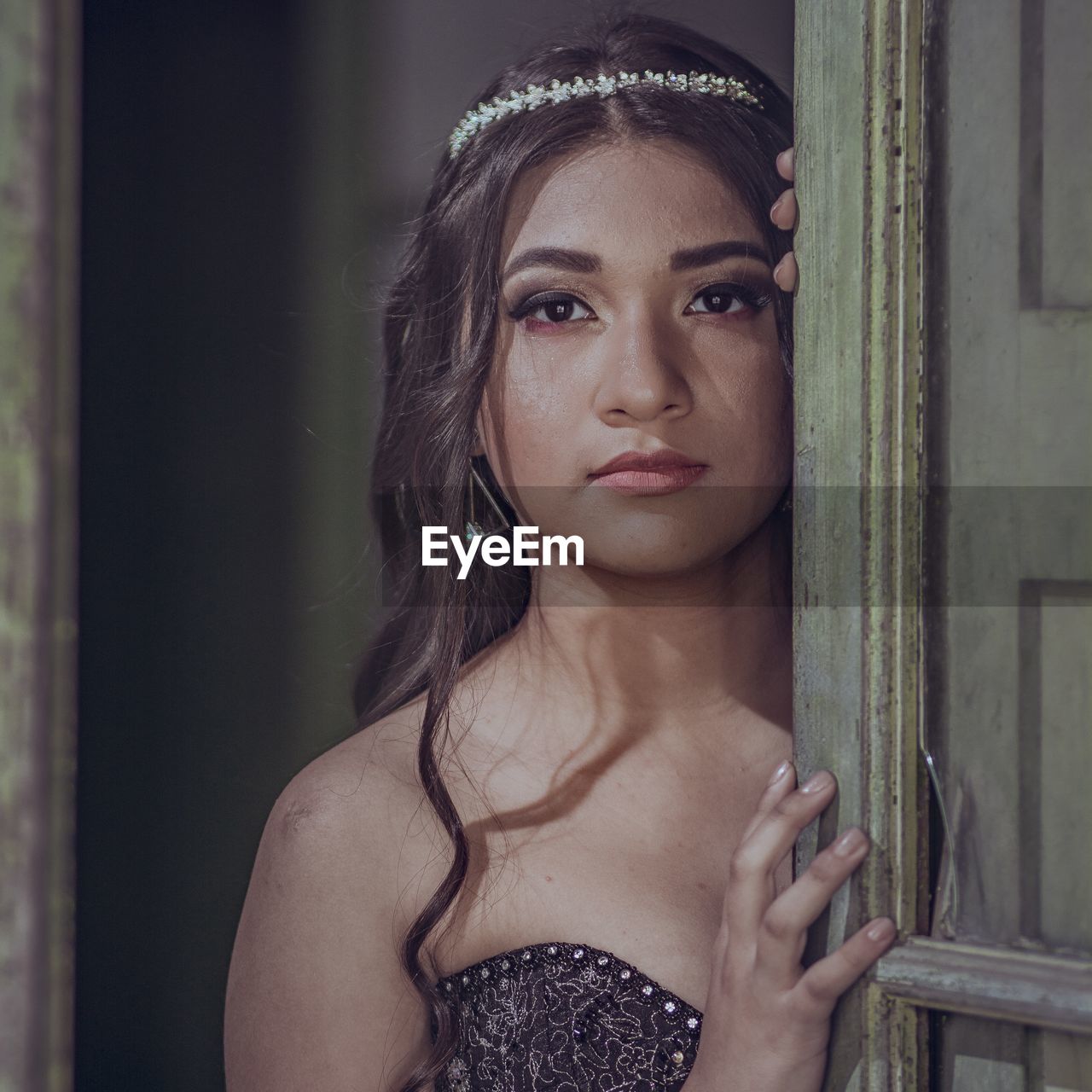 Portrait of beautiful woman wearing tiara while standing behind door