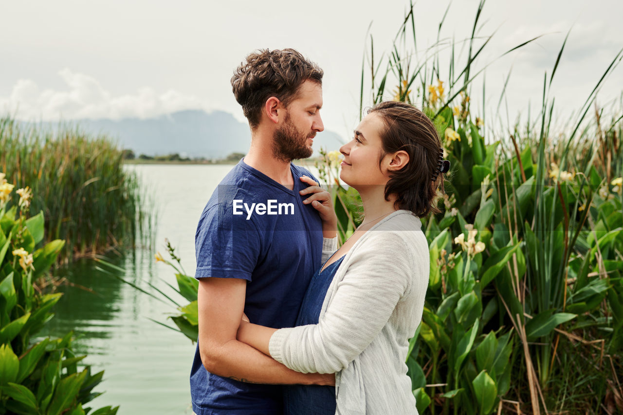 Side view of couple embracing by lake