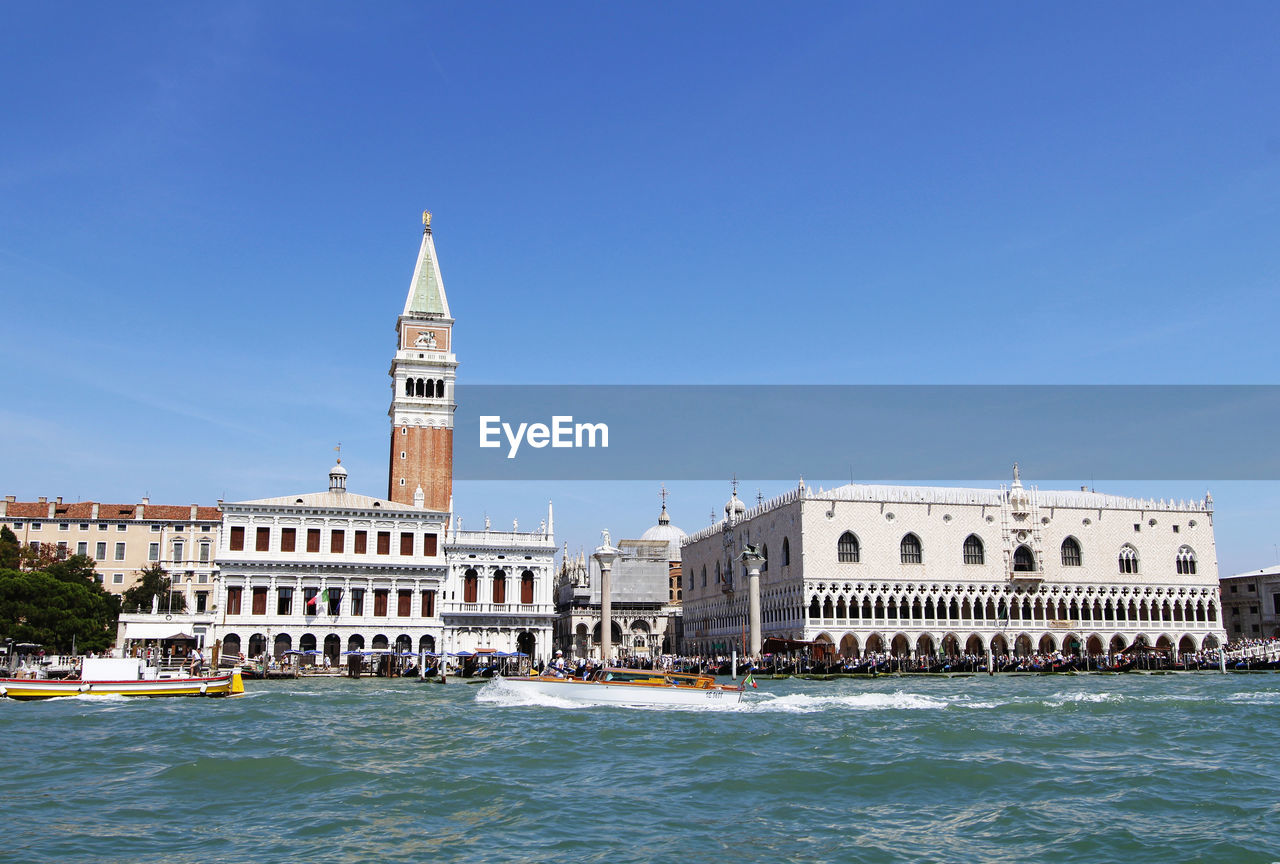 Boats at grand canal by san marco campanile tower against clear blue sky