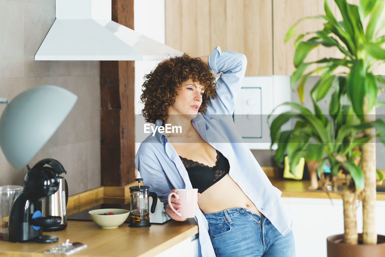 portrait of smiling young woman standing by window