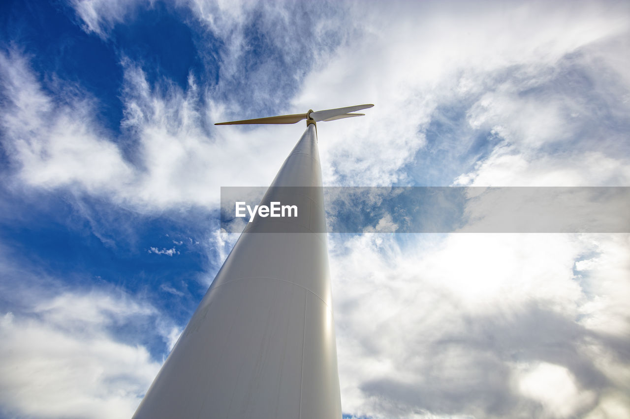 Wind turbine low angle against cloudy blue sky