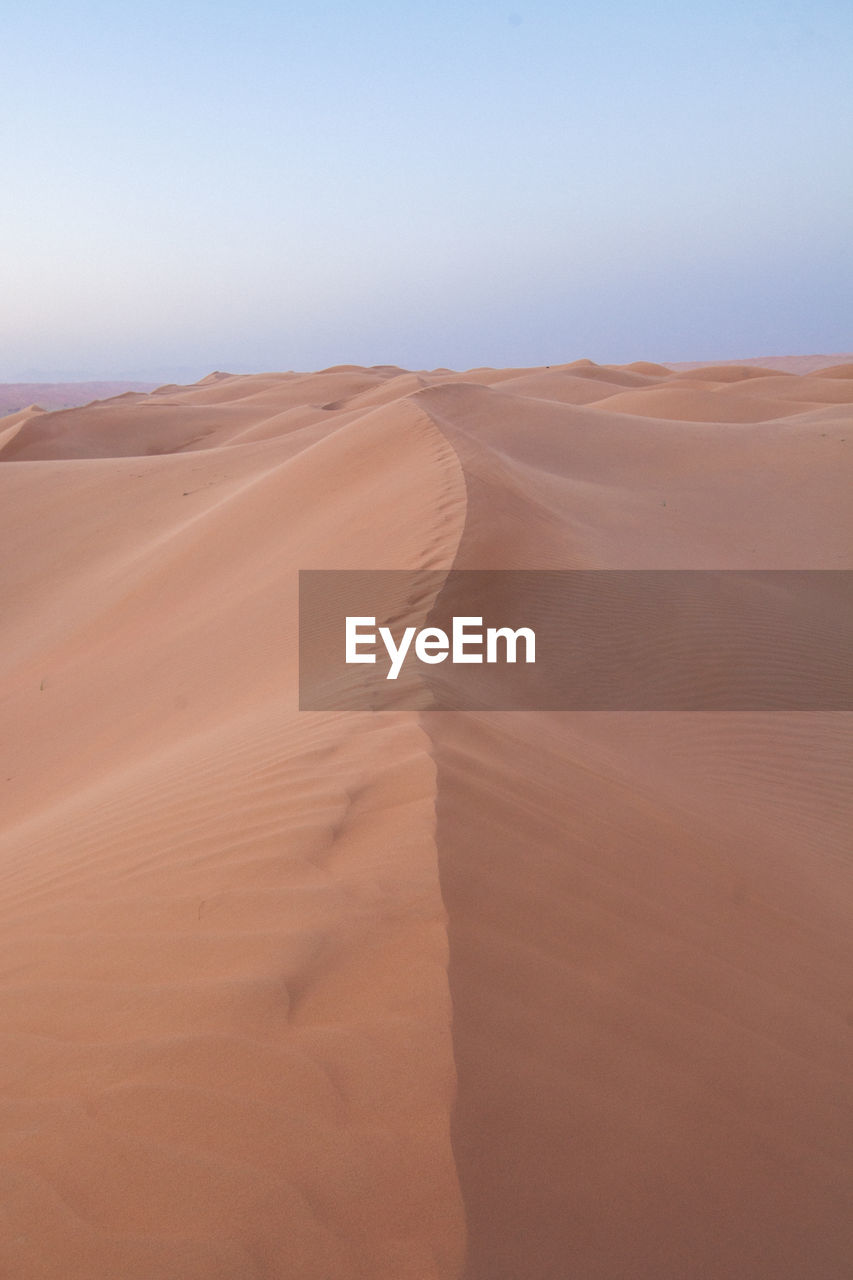 Sand dunes in desert against clear sky