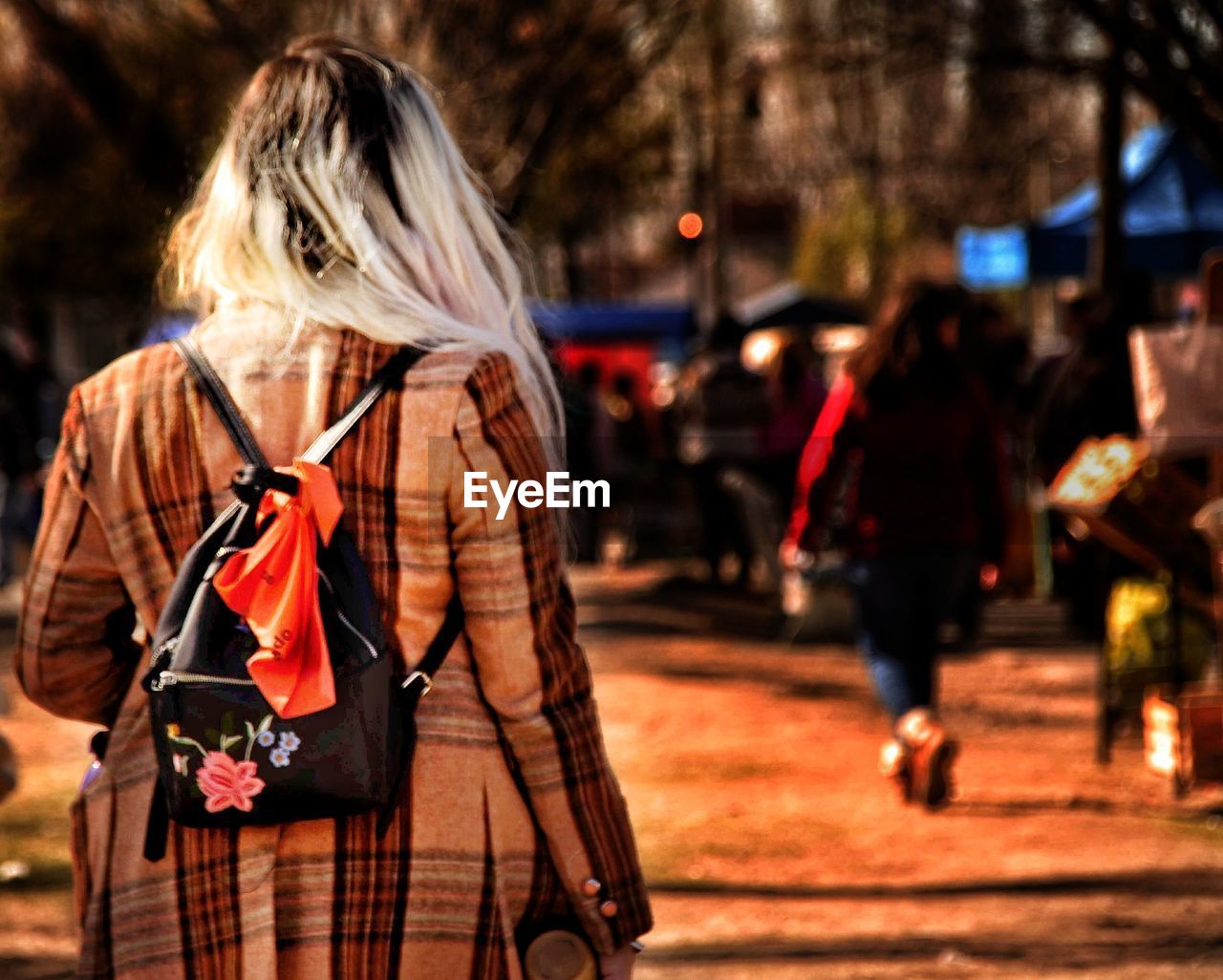 Rear view of woman carrying backpack while walking on street in city