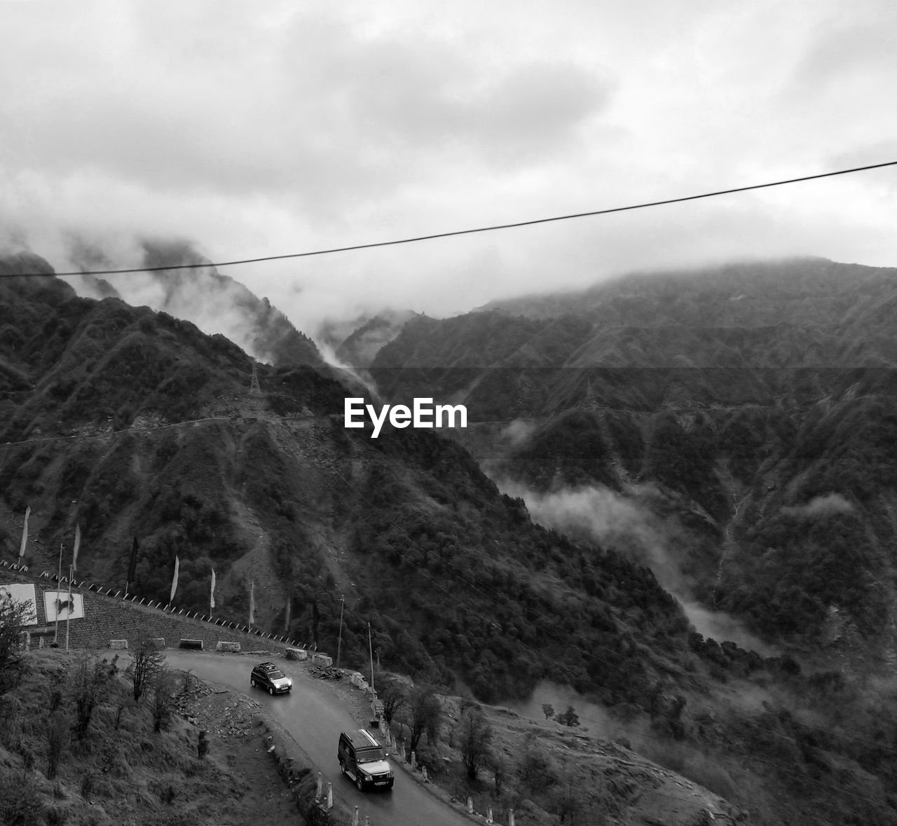 CARS ON ROAD AGAINST MOUNTAIN RANGE