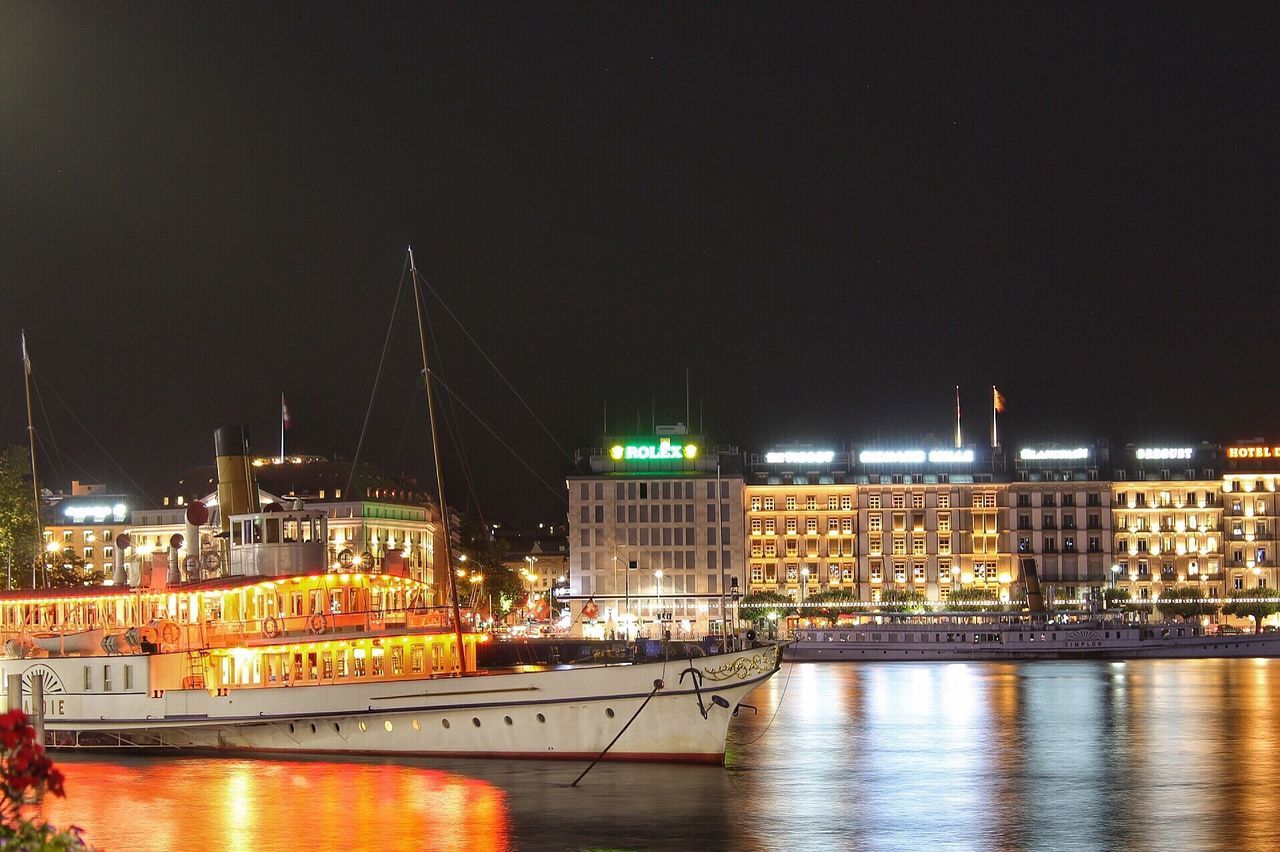 ILLUMINATED CITY BY RIVER AGAINST SKY