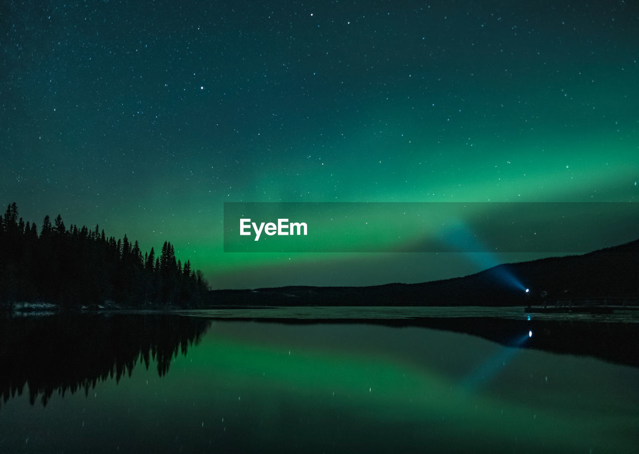 Scenic aurora view of lake against star field at night