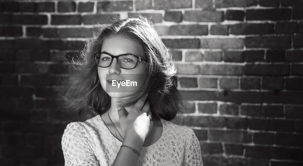 Portrait of teenage girl in eyeglasses against brick wall