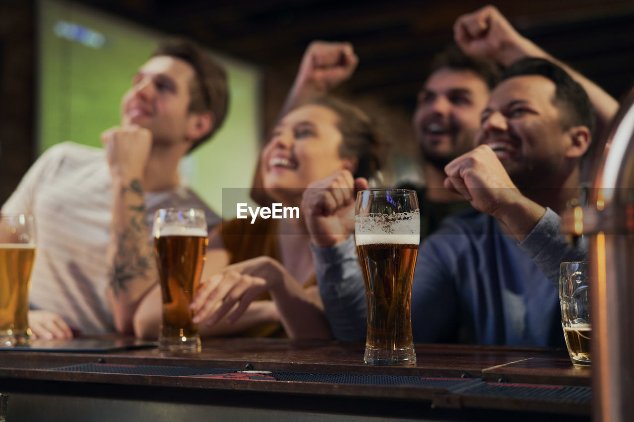 Happy friends watching soccer match at bar