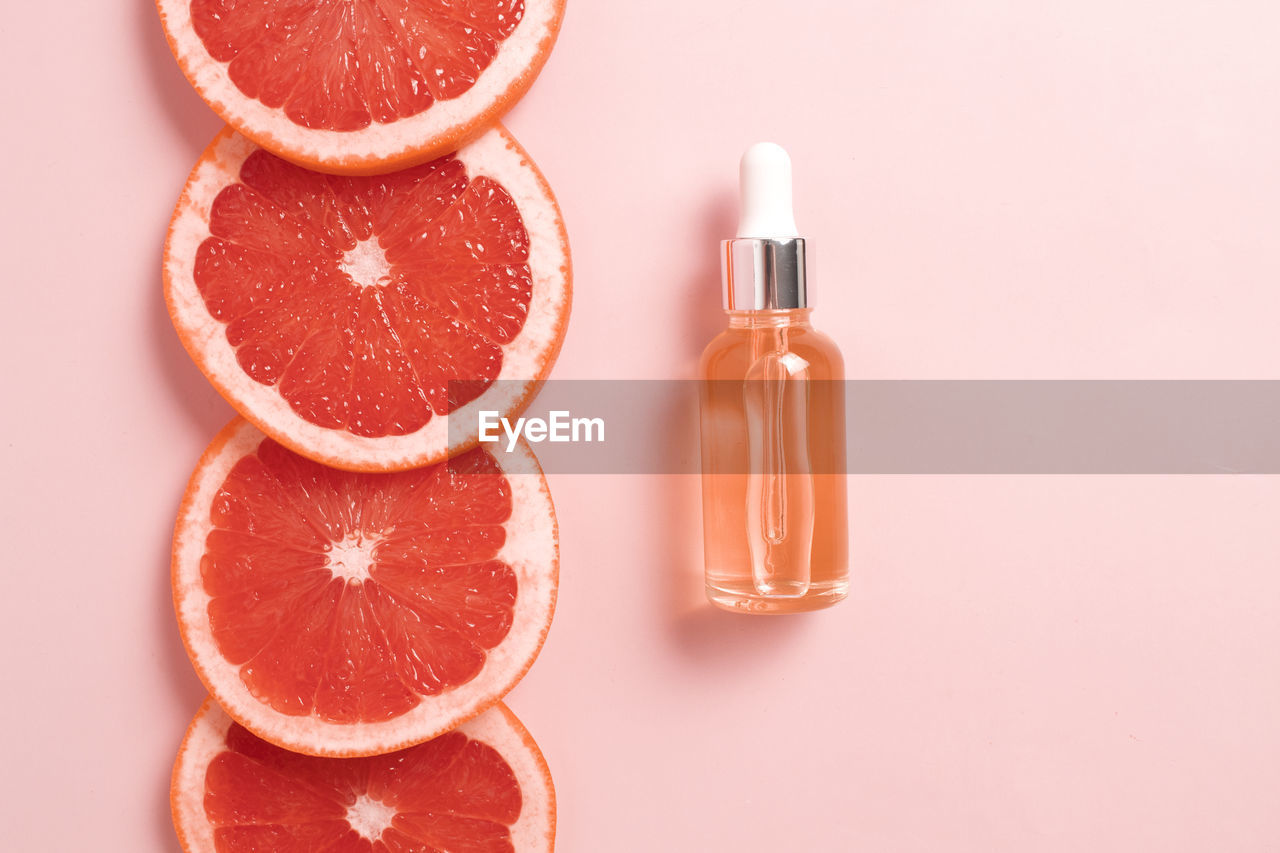 Bottle with dropper of aroma essential oil wich grapefruit fresh slice. flat lay, top view 