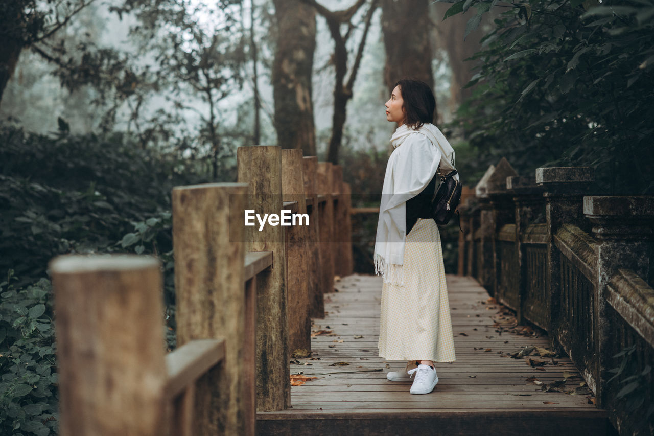 A woman standing in the forest in the cold weather.