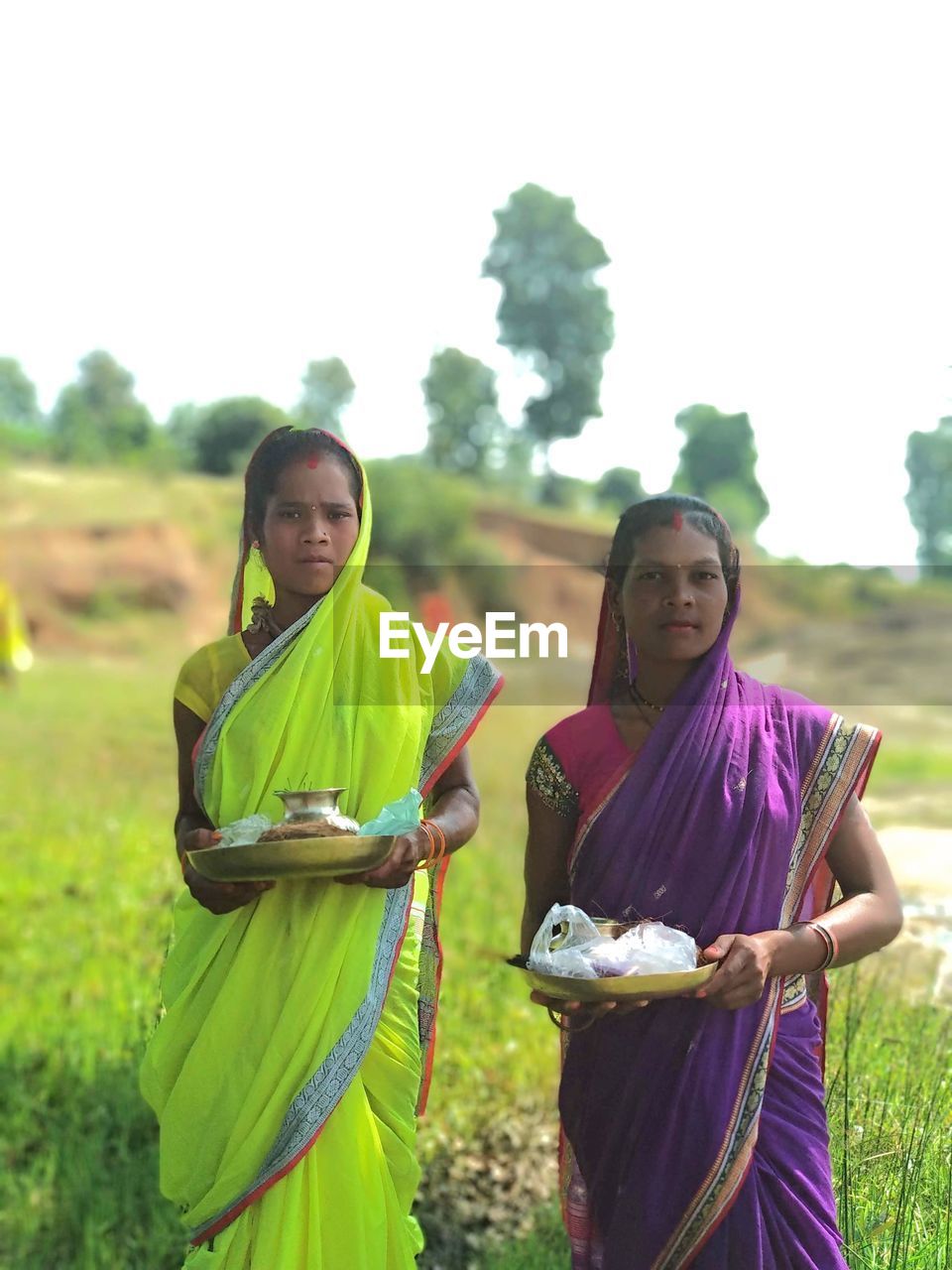 YOUNG FRIENDS STANDING ON FIELD AGAINST SKY