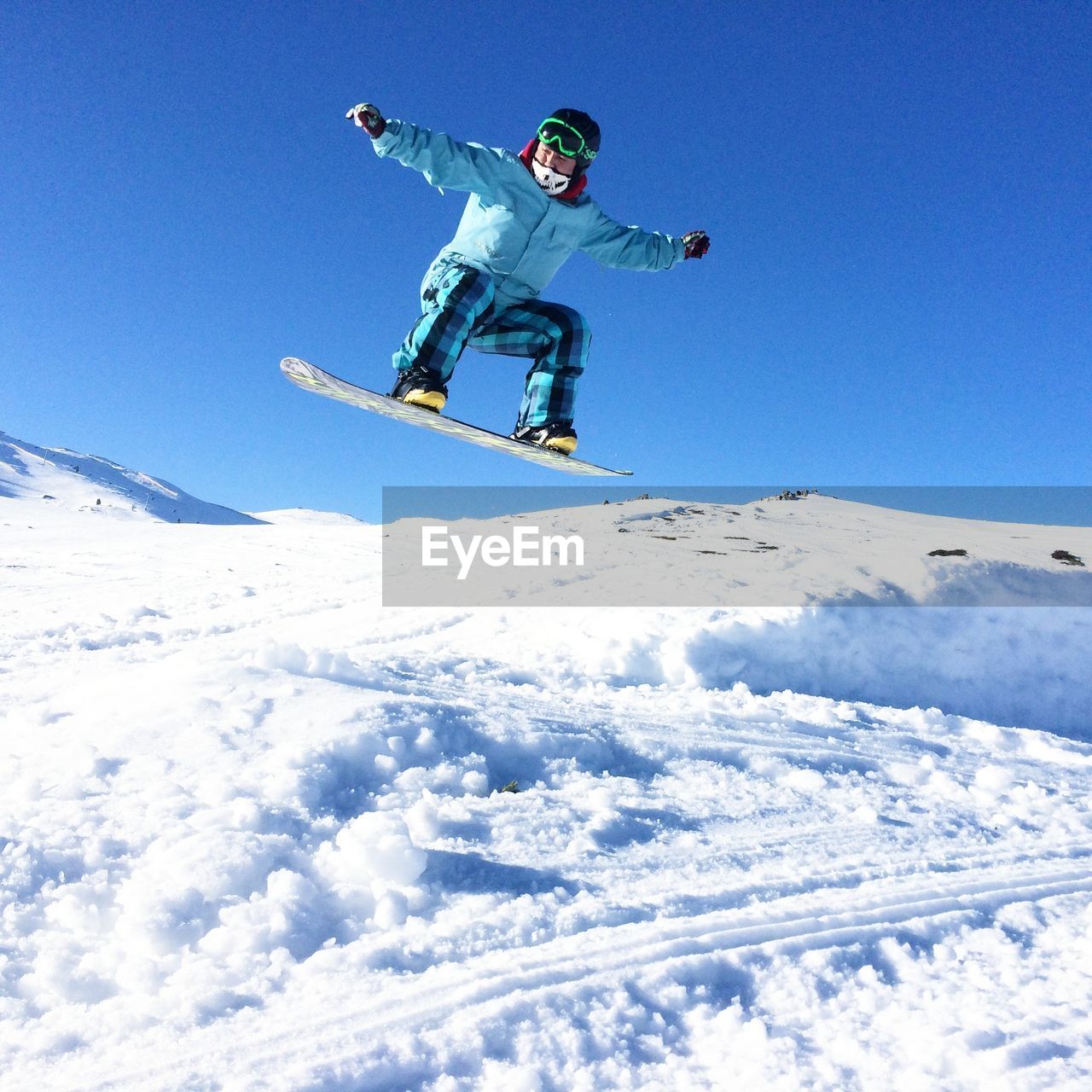 Low angle view of man snowboarding against clear blue sky