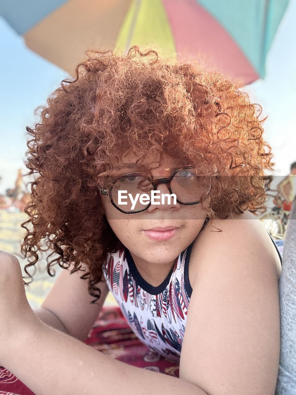 curly hair, human hair, glasses, hairstyle, women, one person, adult, eyeglasses, portrait, smiling, afro, clothing, lifestyles, child, emotion, person, leisure activity, summer, sitting, happiness, female, front view, relaxation, young adult, human face, fun, day, vision care, childhood, casual clothing, teenager, brown hair, nature, headshot, looking at camera, cheerful, skin, lying down, outdoors, enjoyment, looking, arts culture and entertainment