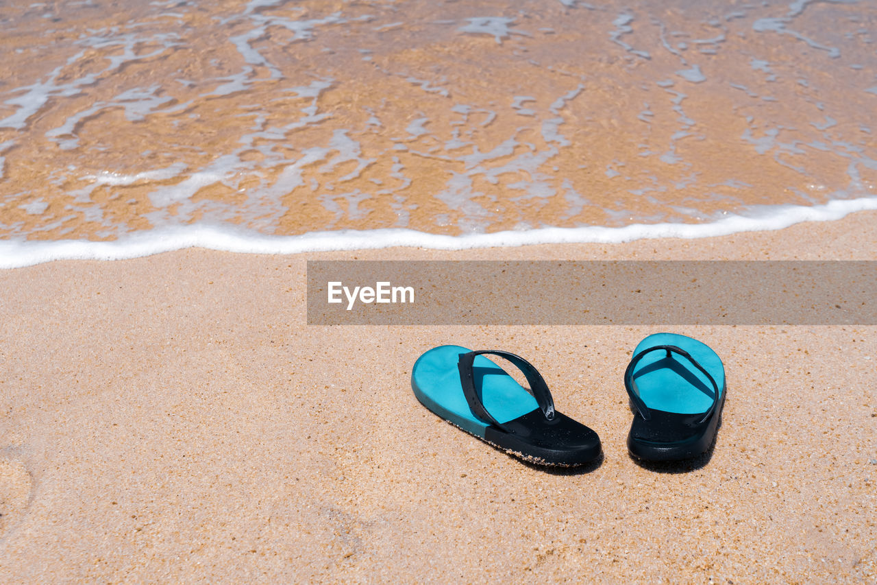 Slippers on the sand at the sea with space , summer holiday and vacation concept.