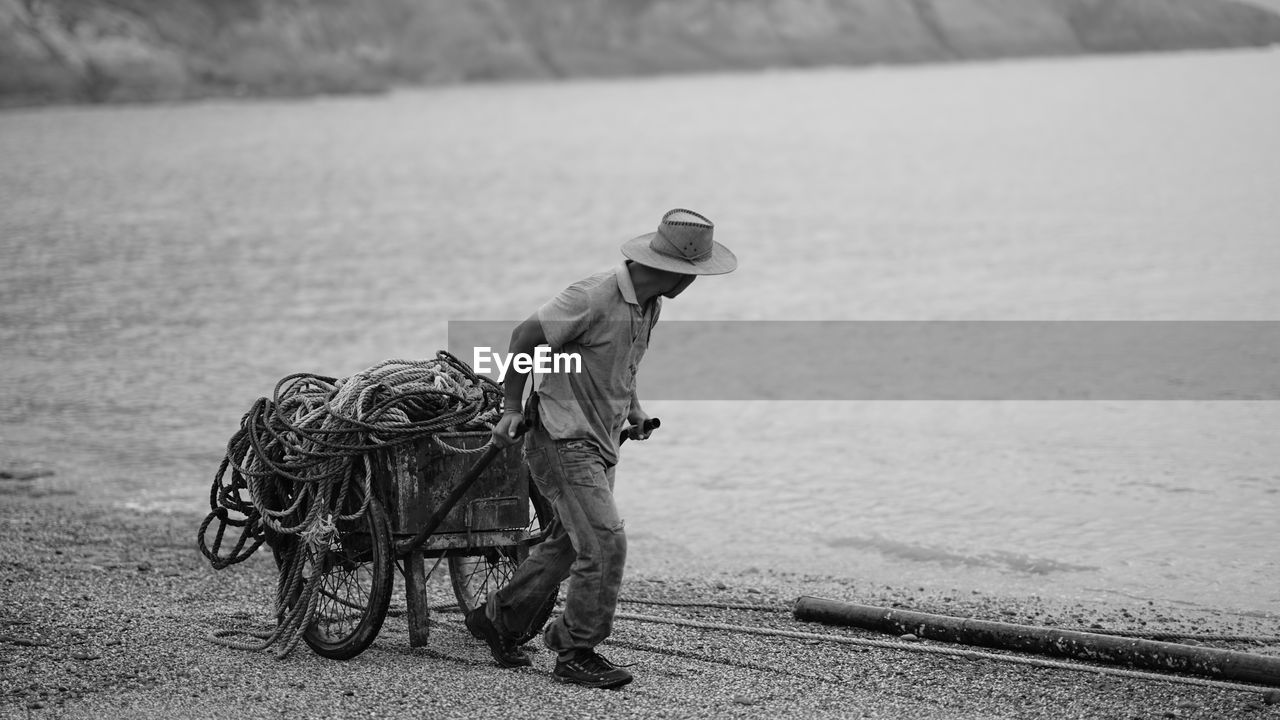 Man pulling cart with ropes at beach