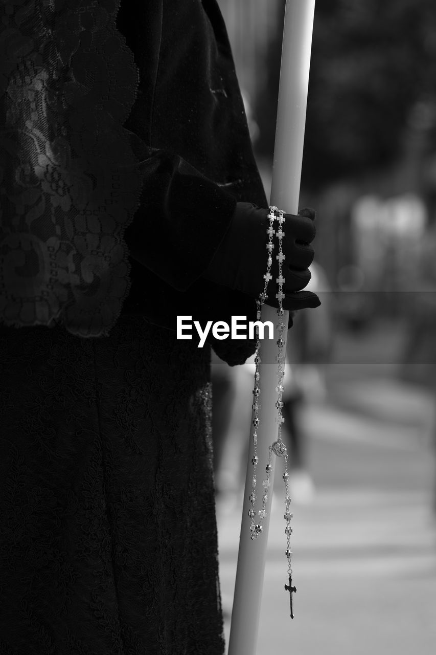 Close-up of person holding crucifix with pole