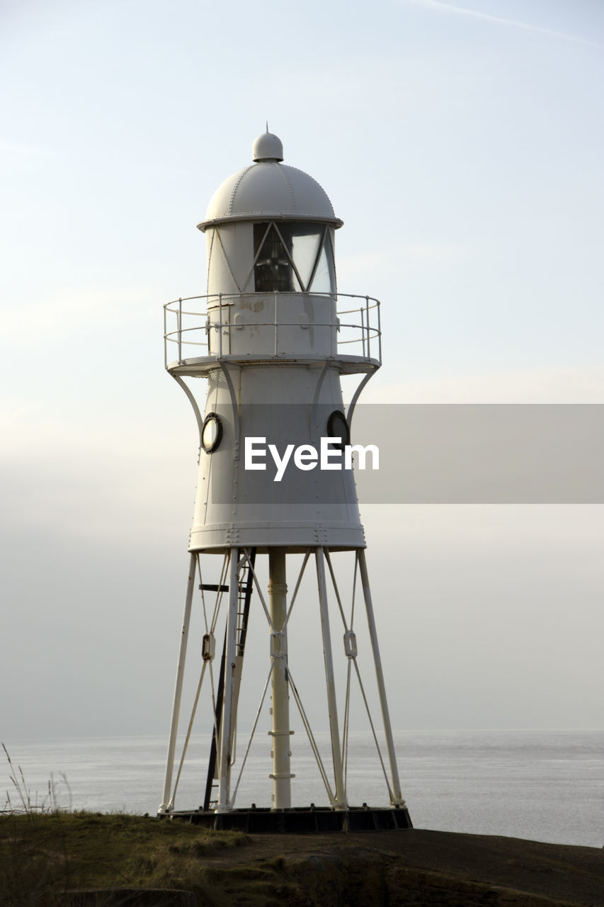 Lighthouse by sea against sky