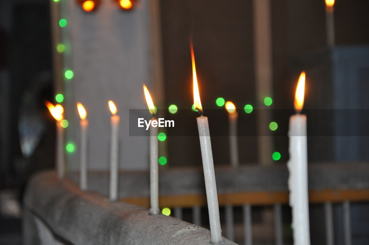 Close-up of illuminated candles against building