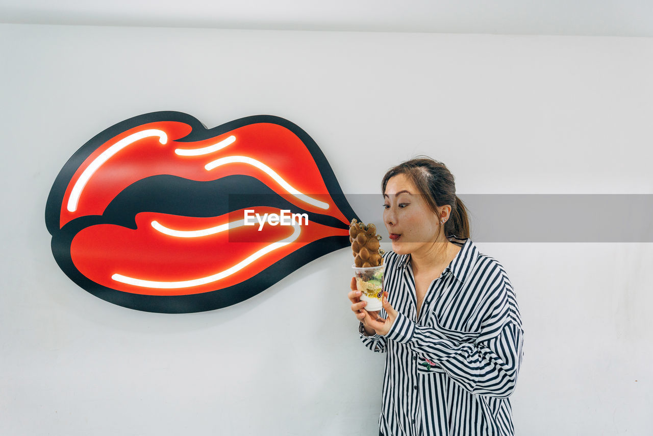 Woman looking at food against wall