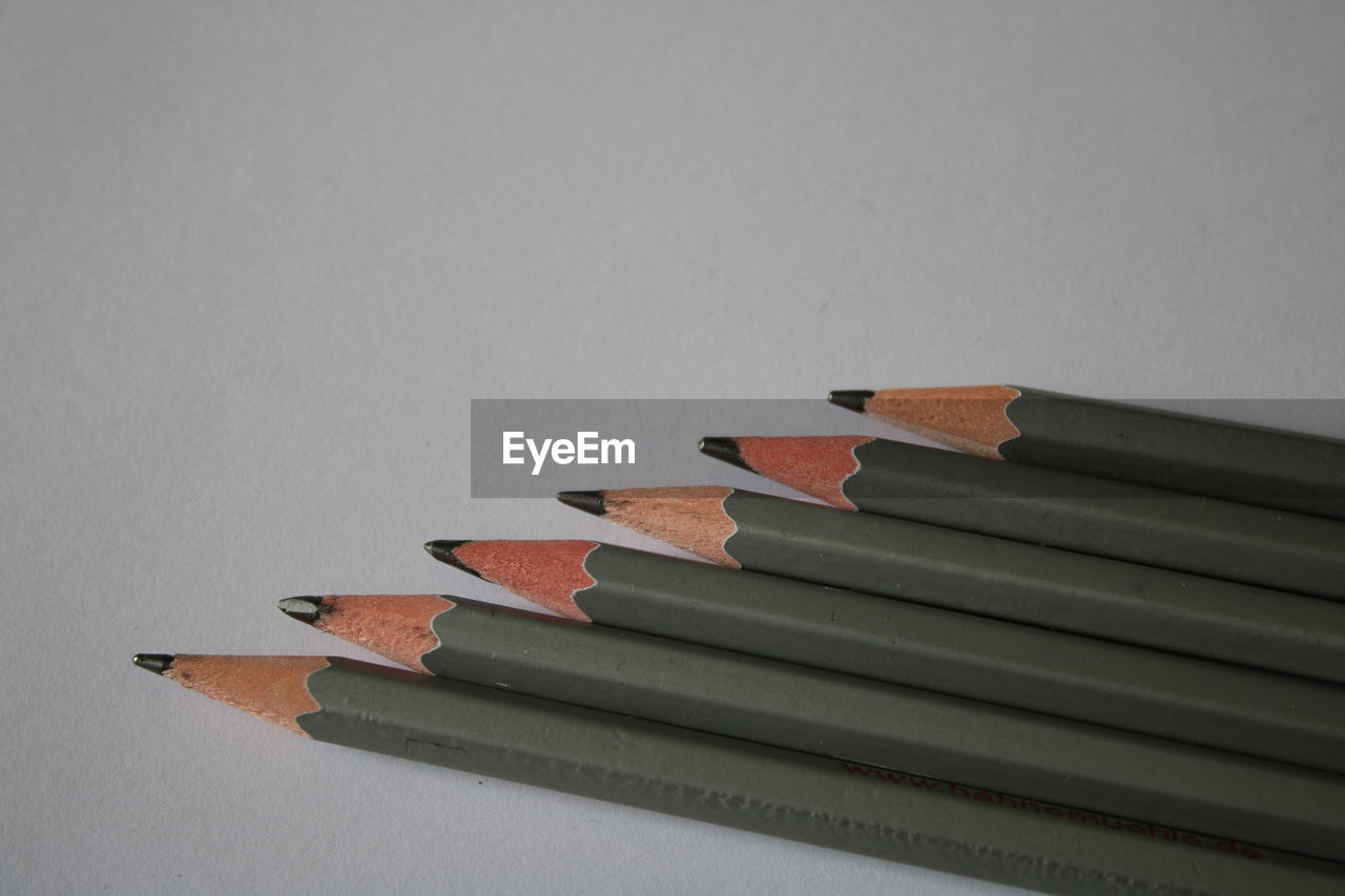 CLOSE-UP OF PENCILS ON TABLE AGAINST WHITE BACKGROUND