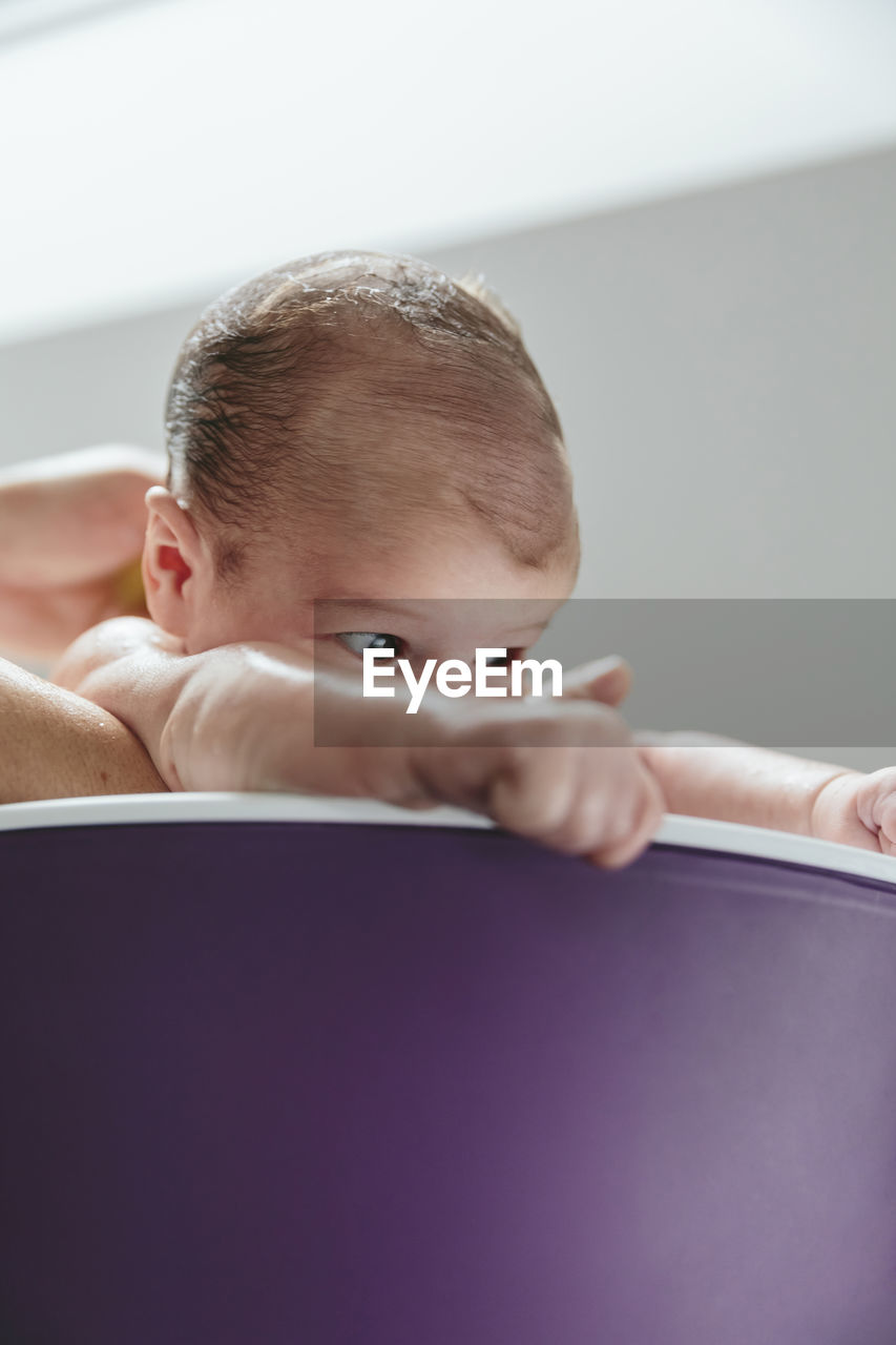 Cropped hands of mother bathing baby girl in bathtub