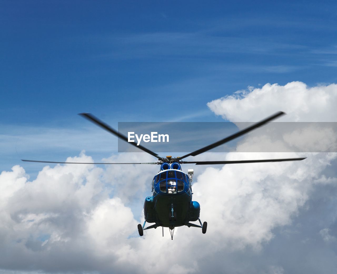 Low angle view of helicopter flying in cloudy sky