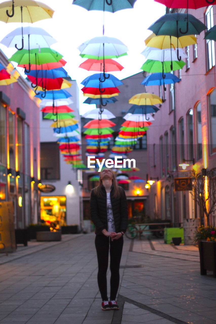 Woman looking at colorful umbrellas over illuminated alley