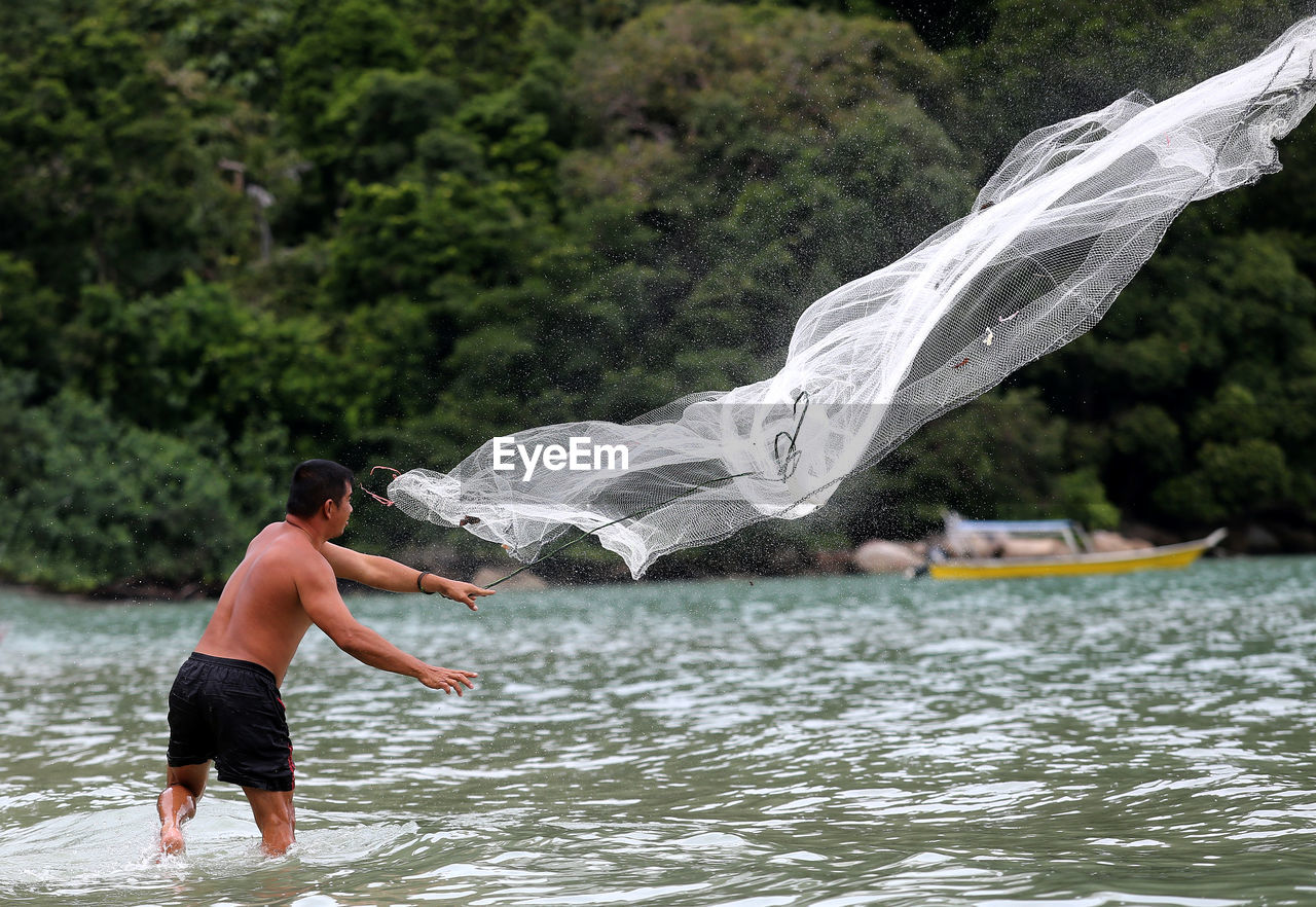 HIGH ANGLE VIEW OF MAN SURFING IN WATER AT PARK