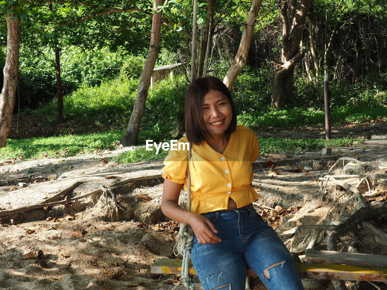 PORTRAIT OF A SMILING YOUNG WOMAN SITTING ON LAND
