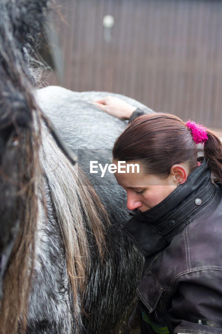 YOUNG WOMAN WITH HORSE IN MOUTH