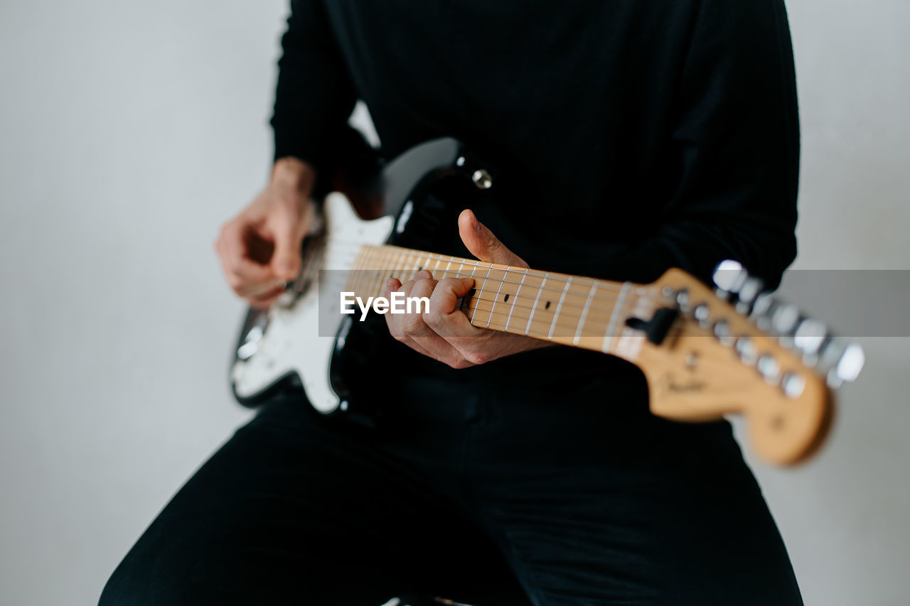 Midsection of man playing electric guitar