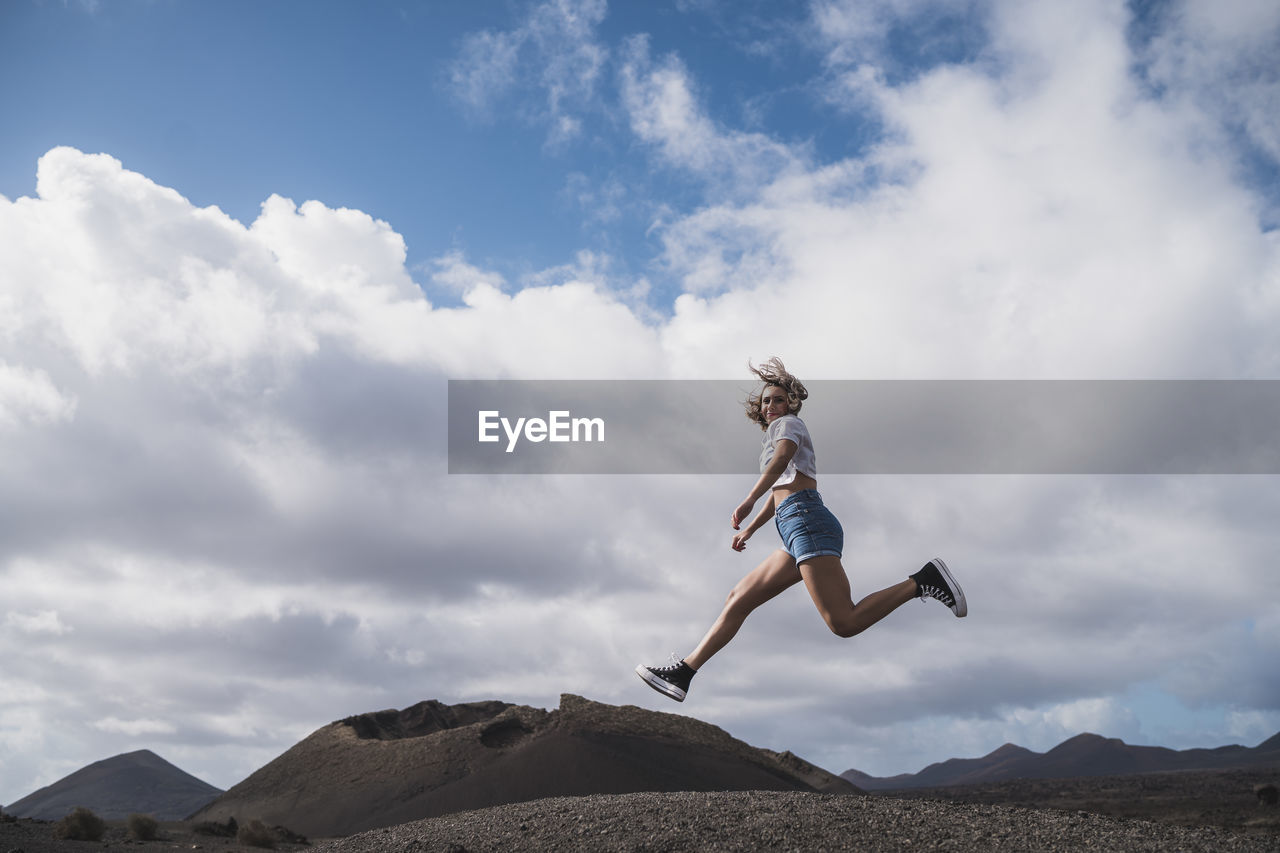 Young woman running against sky at volcano el cuervo, lanzarote, spain