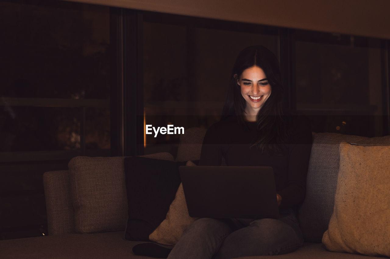 portrait of young woman wearing sunglasses while sitting on sofa at home