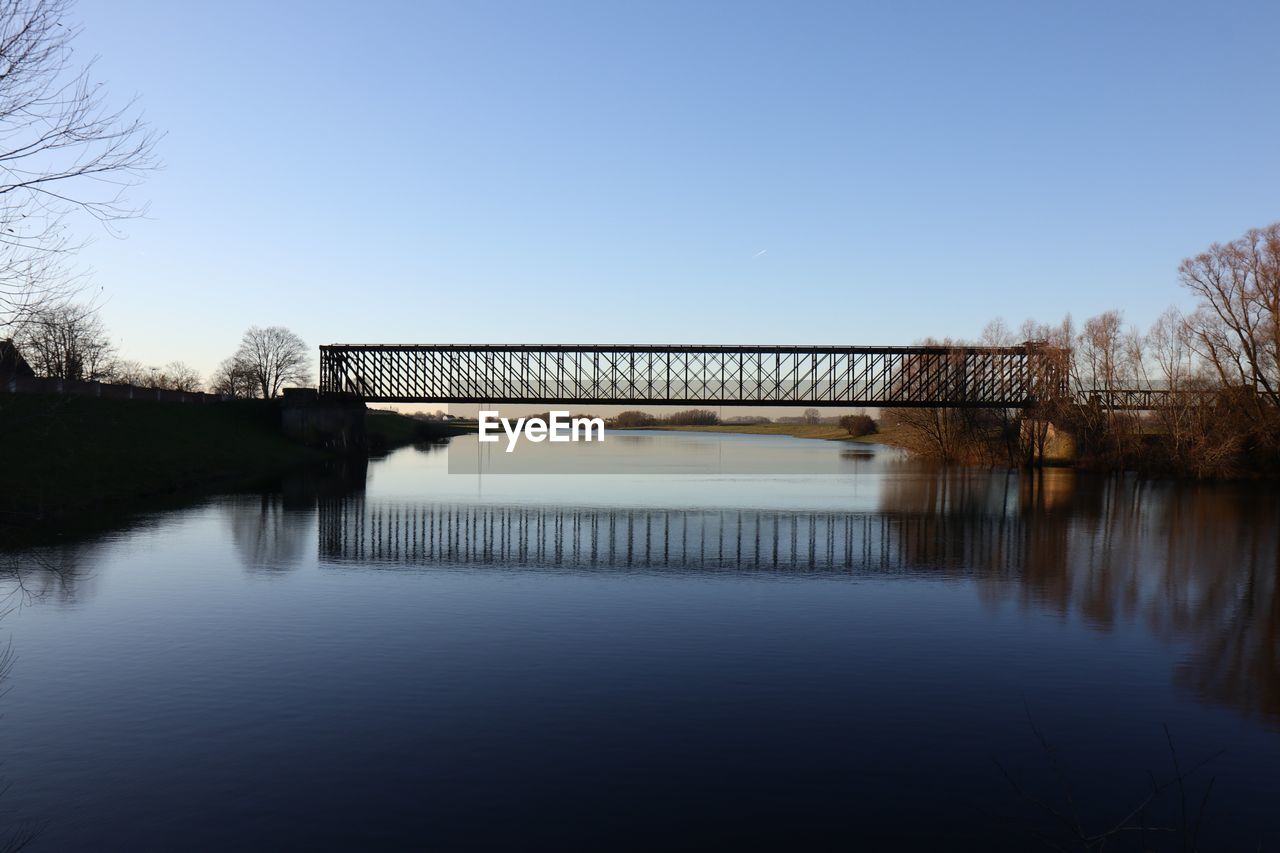 Bridge over lake against clear blue sky