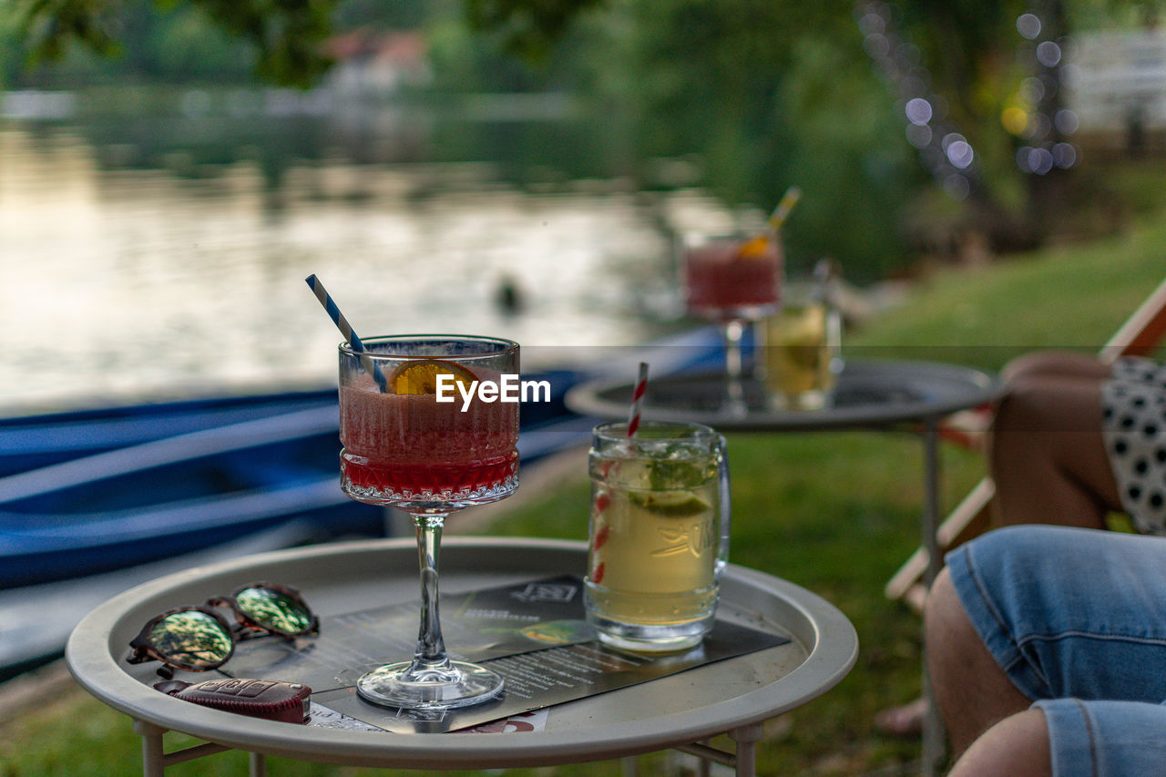 People drinking cocktails served on tables in bar by river